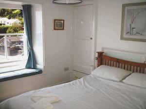 een slaapkamer met een wit bed en een raam bij Balcony Cottage in Cawsand