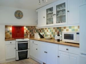 a kitchen with white cabinets and a white microwave at Balcony Cottage in Cawsand