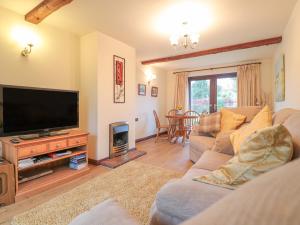 a living room with a couch and a flat screen tv at Berrys Place Farm Cottage in Gloucester