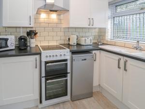 a kitchen with white cabinets and a stove top oven at The Nook in Colwyn Bay