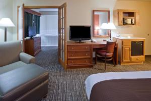 a hotel room with a bed and a desk with a television at AmericInn by Wyndham Alexandria in Alexandria