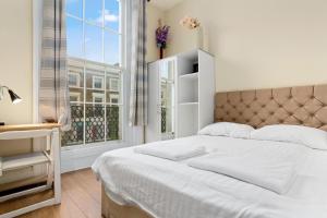a white bedroom with a bed and a window at Spacious 3 Bed Flat with Balcony in Kensington for 6 people in London