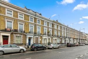 szereg budynków na ulicy miejskiej z zaparkowanymi samochodami w obiekcie Spacious 3 Bed Flat with Balcony in Kensington for 6 people w Londynie
