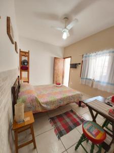 a bedroom with a bed and a desk and a table at Maranata Suítes - 2 minutos de carro até o mar in Peruíbe