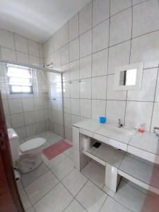 a white bathroom with a toilet and a sink at Maranata Suítes - 2 minutos de carro até o mar in Peruíbe
