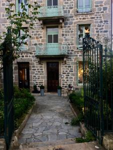 um edifício de pedra com duas varandas e um portão em La Maison de famille em Boën