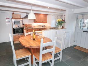 cocina con mesa de madera y sillas blancas en 3 Glendale Cottages, en Dartmouth