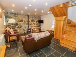 a living room with a couch and a stone wall at Craig Y Deryn in Tywyn