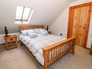 a bedroom with a wooden bed and a window at Craig Y Deryn in Tywyn