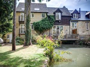a large stone house with a pond in front of it at Cider Press in Burford