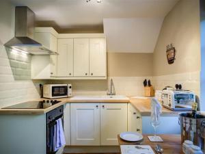 a kitchen with white cabinets and a counter top at Cider Press in Burford