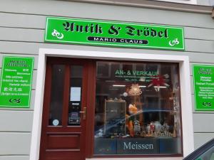 przednia część sklepu z zielonym znakiem nad drzwiami w obiekcie Ferienwohnung Claus w mieście Miśnia
