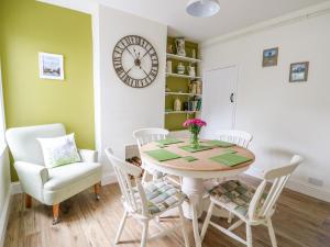 ein Esszimmer mit einem Tisch, Stühlen und einer Uhr in der Unterkunft Coorie Cottage in Great Yarmouth