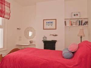 a bedroom with a red bed with two pillows on it at The Cottage, 13 Clarence Hill in Dartmouth
