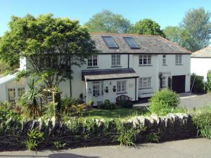 a white house with a stone wall at Orchard Lodge in Boscastle