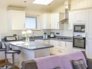 a kitchen with white cabinets and a counter top at Woodpecker Lodge in Skipton