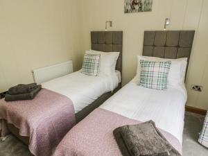 two twin beds in a room with two blankets at Woodpecker Lodge in Skipton