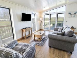 sala de estar con 2 sofás y TV de pantalla plana en Woodpecker Lodge en Skipton