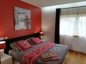 a bedroom with a bed with red walls and a window at Villa Confort - FURADOURO in Ovar