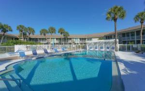 a swimming pool with chairs and palm trees in a resort at King Bed - Walk to St. Armand's Circle and Lido Beach in Minutes! in Sarasota