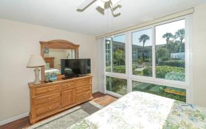 Un dormitorio con una cama y un televisor y una ventana. en King Bed - Walk to St. Armand's Circle and Lido Beach in Minutes!, en Sarasota