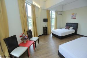 雪邦的住宿－JAM Hotel Kota Warisan Sepang @ ERL Salak Tinggi, KLIA 1-2 & F1，酒店客房带两张床和一张红色的桌子以及椅子。