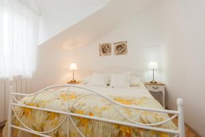 ein weißes Bett in einem weißen Zimmer mit zwei Lampen in der Unterkunft Promaja in Kaštela