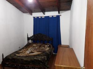 Cama en habitación con cortina azul en Lo de Charly en Villa Carlos Paz