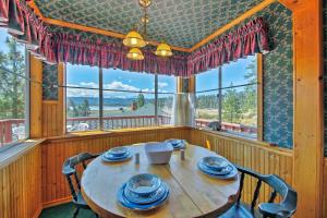 a dining room with a table and chairs and windows at Walk to Lake Cabin with Deck and Views in Fawnskin in Fawnskin