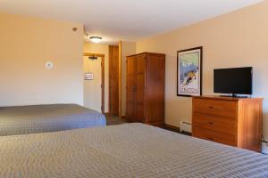 a hotel room with two beds and a flat screen tv at The Black Bear Lodge at Stratton Mountain Resort in Stratton Mountain