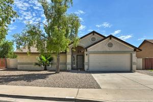 a house with a tree in front of a driveway at Updated Mesa Home with Spacious Backyard and Fire Pit! in Mesa