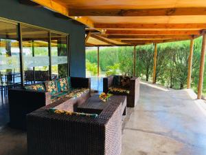 a covered patio with couches and tables and windows at Rangi Moana in Hanga Roa