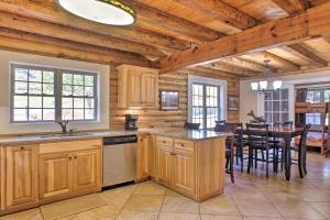 a kitchen with wooden cabinets and a dining room with a table at Scottsboro Cabin with Fire Pit and Stocked Pond Access in Scottsboro