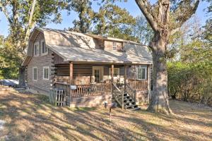 a log cabin with a porch and a tree at Scottsboro Cabin with Fire Pit and Stocked Pond Access in Scottsboro