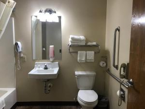 a bathroom with a toilet and a sink and a mirror at Heartland Hotel & Suites in Rock Valley
