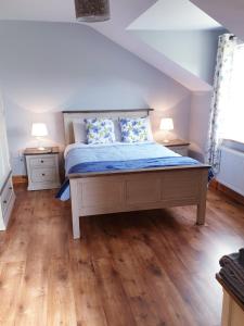 1 dormitorio con 1 cama con sábanas azules y suelo de madera en Nellies Cottage B&B, en Kilcogy