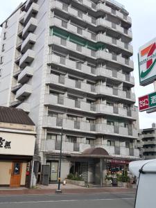 a tall apartment building with balconies on a street at Nomad Apartment Stay in Kumamoto