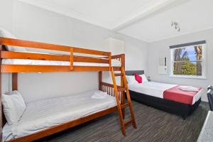 a bedroom with two bunk beds and a window at The Wauchope Motel in Wauchope