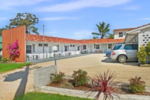 un coche aparcado en un estacionamiento frente a un motel en The Wauchope Motel en Wauchope