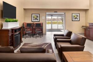 Hawthorn Suites By Wyndham Oak Creek/Milwaukee Airport في ميلووكي: غرفة انتظار مع كنب وتلفزيون بشاشة مسطحة