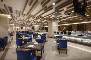 a restaurant with blue chairs and tables and a bar at Ramada Plaza by Wyndham Enshi in Enshi