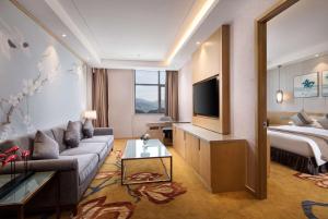 a living room with a couch and a bed at Ramada Plaza by Wyndham Enshi in Enshi