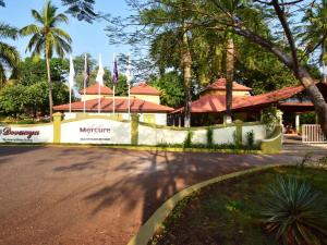 uma cerca em frente a um edifício com palmeiras em Mercure Goa Devaaya Resort em Old Goa