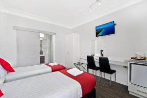 a hotel room with two beds and a tv at The Wauchope Motel in Wauchope