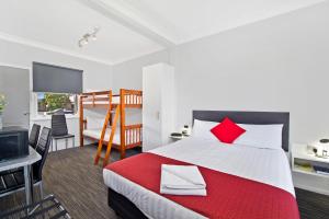 a bedroom with a large bed with red pillows at The Wauchope Motel in Wauchope