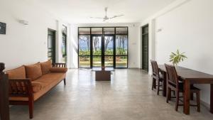 uma sala de estar com um sofá, uma mesa e cadeiras em Villa Nilnara em Ahungalla