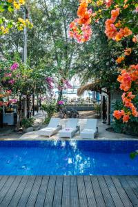 a swimming pool with chairs and trees and flowers at Bale Sampan Boutique Bungalows in Gili Trawangan
