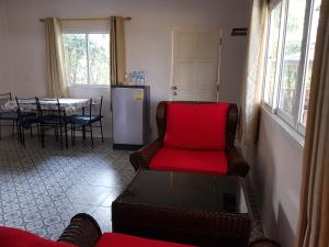 Nadee resort في أودون ثاني: غرفة معيشة مع أريكة حمراء وطاولة