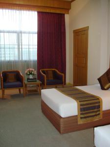 a hotel room with two beds and two chairs at Chiang Mai Phucome Hotel in Chiang Mai