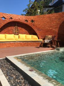 a swimming pool with a couch and a brick wall at Nine Hotel Chiangmai in Chiang Mai